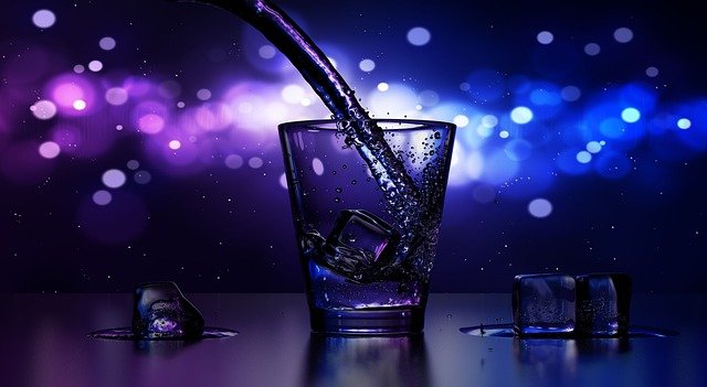 Drink som håller på att bli hälld med blått klubbljus i bakgrunden